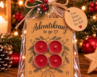 Könnte beinhalten: Ein durchsichtiger Plastikbeutel mit vier roten Teelichtern auf einer beigen Karte mit der Aufschrift Adventskranz to go und einem runden Anhänger mit der Aufschrift Eine kleine Auszeit für dich, verziert mit einem Tannenzweig und roten Beeren.