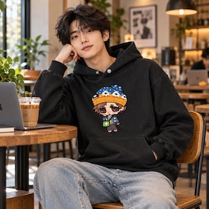Peut inclure: Un sweat-shirt à capuche noir à manches longues avec une impression graphique représentant un personnage de dessin animé portant un bonnet bleu et orange à motifs de pattes blanches, une veste bleue et un sac vert avec une croix blanche.