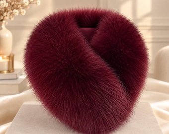 May include: A deep burgundy faux fur collar with a thick, plush texture and a rounded, voluminous shape. The accessory features long, soft fibers in a rich, dark red hue, designed to wrap around the neck area with a dense, full appearance.