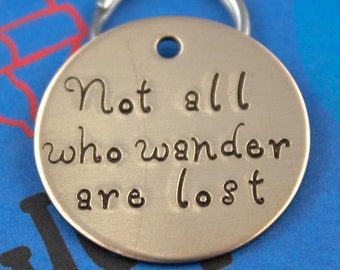 May include: Silver key chain with a round tag that reads "Not all who wander are lost".