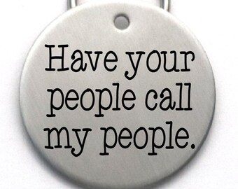 May include: Silver dog tag with the text "Have your people call my people."