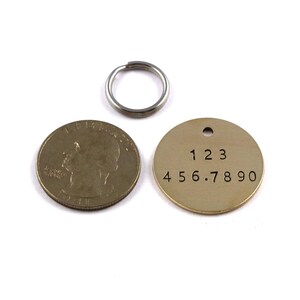 May include: A round brass tag with the numbers 123 456.7890 engraved on it. The tag is attached to a silver key ring.
