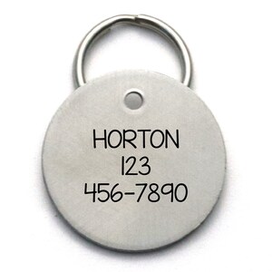 Pu&ograve; includere: Un'etichetta rotonda in argento per animali domestici con un portachiavi. L'etichetta &egrave; incisa con il nome "HORTON" e il numero di telefono "456-7890".