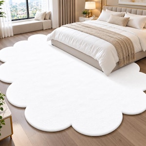 May include: A large, solid white area rug with a scalloped, cloud-like edge. The rug features a soft, plush texture and is shaped with multiple rounded curves along its entire perimeter, creating a distinct, non-rectangular silhouette.