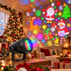 May include: A black cylindrical Christmas light projector sits on a wooden surface, casting colorful holiday patterns of Santa Claus, a snowman, reindeer, snowflakes, and gift boxes onto a wall in a room decorated for the holidays.