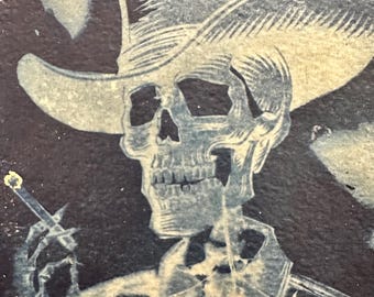 May include: A high-contrast graphic print featuring a skeleton wearing a cowboy hat and a collared shirt. The skeleton is depicted in a light, off-white tone against a dark, textured background, holding a lit cigarette between its fingers.