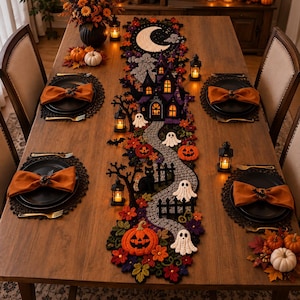 May include: A long, crocheted Halloween table runner featuring a winding stone path, a haunted house, ghosts, pumpkins, a black cat, and a crescent moon. The runner is decorated with autumn leaves and small black lanterns.