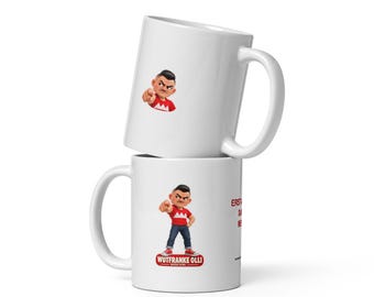 Puede incluir: Dos tazas de cerámica blanca apiladas verticalmente. La taza inferior presenta un personaje de dibujos animados con camisa roja y jeans azules señalando hacia adelante, con el texto WUTFRANKE OLLI debajo. El lado muestra texto rojo ERST A... DANN M...