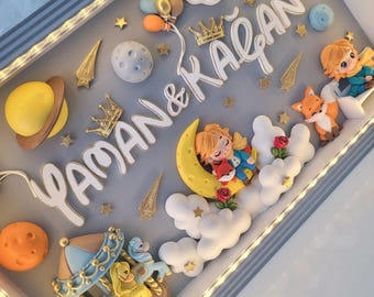 Puede incluir: Un marco tipo caja con luces LED integradas que contiene una decoración de pared en 3D. La escena presenta el texto YAMAN & KAĞAN, una luna creciente amarilla, un carrusel, planetas, estrellas, nubes y figuras de un niño y un zorro.