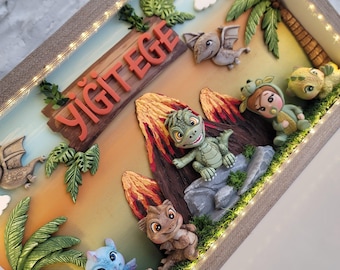 Puede incluir: Un marco tipo caja con iluminación LED integrada que contiene un diorama 3D de un paisaje prehistórico. Incluye figuras de arcilla de dinosaurios, un niño con disfraz de dinosaurio, palmeras, volcanes y un letrero con el nombre YİĞİT EGE.
