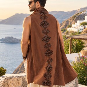 May include: A sleeveless brown tunic featuring a vertical black geometric pattern running down the center back. The garment has a high collar and a loose, flowing fit that extends to the mid-thigh, worn over light-colored trousers.