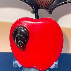 May include: A red glass apple with a black leaf. The apple is a vintage style and has a shiny finish.