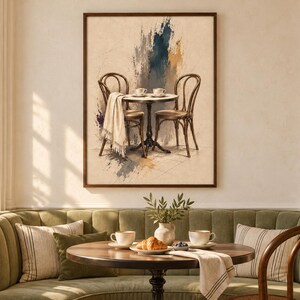 Peut inclure: Une impression d'art encadrée représentant une table de bistrot avec deux chaises et un tissu drapé. L'œuvre présente des coups de pinceau abstraits dans des tons bleu, marron et crème, illustrant une scène de café avec deux petites tasses.