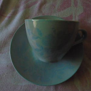 May include: A blue and white floral teacup and saucer set. The cup has a handle and a floral design. The saucer is plain blue.
