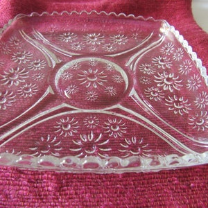 K&ouml;nnte beinhalten: Eine klare Glasservierplatte mit einem gewellten Rand und einem Blumenmuster. Die Platte ist in vier Abschnitte unterteilt.