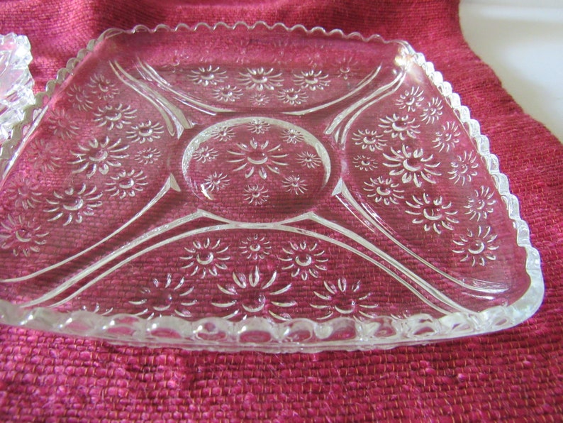 K&ouml;nnte beinhalten: Eine klare Glasservierplatte mit einem gewellten Rand und einem Blumenmuster. Die Platte ist in vier Abschnitte unterteilt.