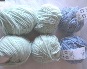 May include: Six balls of yarn, three light blue and three pale green, arranged in two rows of three. The yarn balls have labels with text in a foreign language.