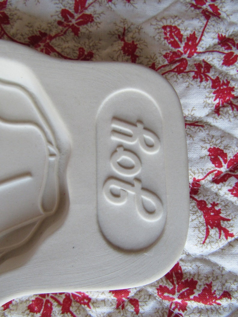 Puede incluir: Plato para hornear de cer&aacute;mica blanca con una forma ovalada en relieve y la palabra "Pop" grabada en el lateral.