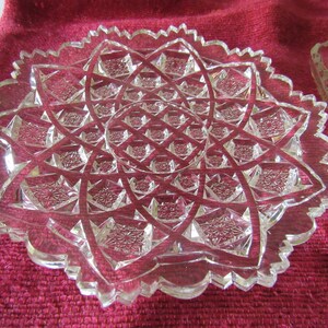 K&ouml;nnte beinhalten: Ein klarer Glasteller mit einem gewellten Rand und einem geometrischen Muster. Der Teller ist aus geschnittenem Glas und hat ein Sternmuster.
