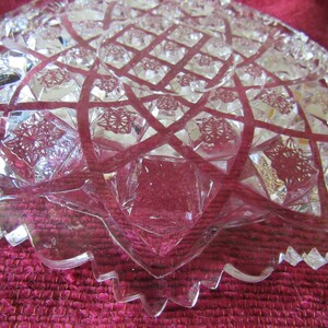 K&ouml;nnte beinhalten: Eine klare Glassch&uuml;ssel mit einem geschliffenen Glasdesign. Die Sch&uuml;ssel hat einen gewellten Rand und ein Sternmuster in der Mitte.
