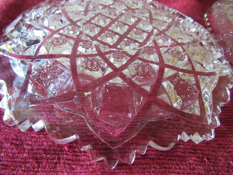 K&ouml;nnte beinhalten: Eine klare Glassch&uuml;ssel mit einem geschliffenen Glasdesign. Die Sch&uuml;ssel hat einen gewellten Rand und ein Sternmuster in der Mitte.