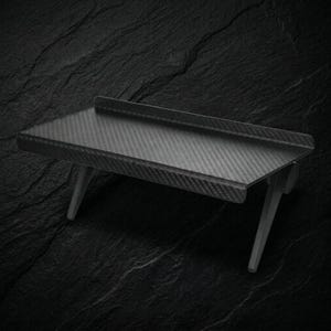 May include: A rectangular shelf featuring a dark gray carbon fiber pattern with a raised back edge and two angled support legs extending downward from the underside, providing a stable structure for mounting or display purposes.