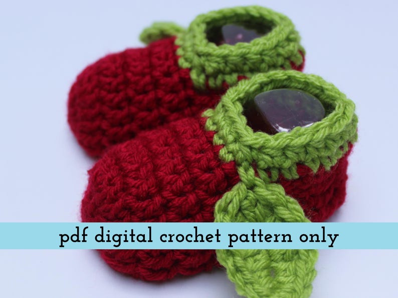 K&ouml;nnte beinhalten: Ein Paar handgefertigte Baby-H&auml;kel-Schuhe in leuchtendem Rot, mit gr&uuml;nen Verzierungen und Bl&auml;ttern. Die Schuhe haben ein einzigartiges Design und sind perfekt f&uuml;r Neugeborene. Der Text "pdf digital crochet pattern only" ist zu sehen.