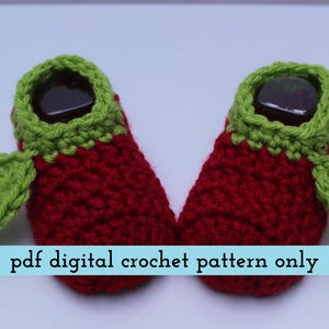 K&ouml;nnte beinhalten: Ein Paar handgefertigte Baby-H&auml;kel-Booties im Erdbeer-Design. Die Booties sind rot mit gr&uuml;nen Verzierungen und Blattakzenten. Der Text "pdf digital crochet pattern only" wird auf hellblauem Hintergrund angezeigt.