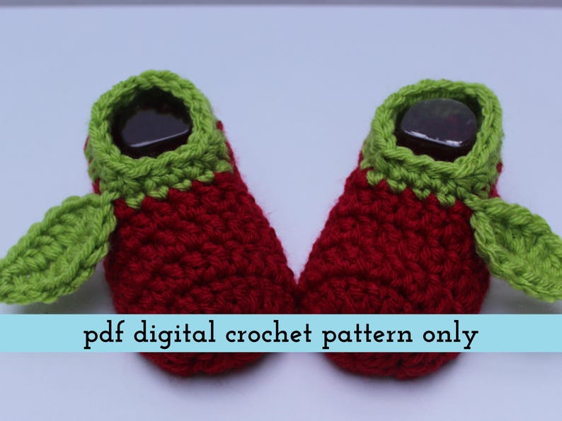 K&ouml;nnte beinhalten: Ein Paar handgefertigte Baby-H&auml;kel-Booties im Erdbeer-Design. Die Booties sind rot mit gr&uuml;nen Verzierungen und Blattakzenten. Der Text "pdf digital crochet pattern only" wird auf hellblauem Hintergrund angezeigt.