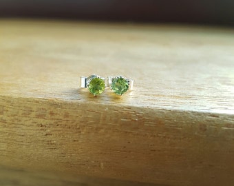 May include: A pair of silver earrings with green gemstone studs.