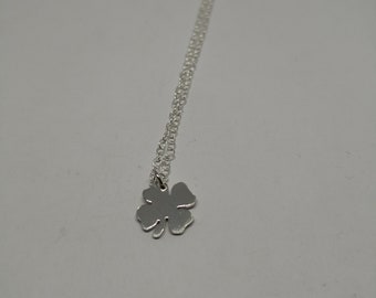 May include: A silver necklace with a four-leaf clover pendant.