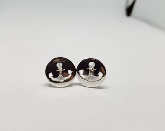 May include: A pair of silver stud earrings featuring an anchor design. The anchors are cut out of the metal, creating a delicate and minimalist look.