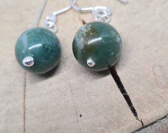 May include: A pair of silver earrings with green agate stone drops. The stones have a mottled green and white pattern.