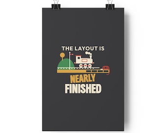 May include: A dark grey wall poster featuring a graphic of a small train on tracks with a green hill and the text THE LAYOUT IS NEARLY FINISHED in white and yellow lettering. The design includes a red signal and a coiled red rope.