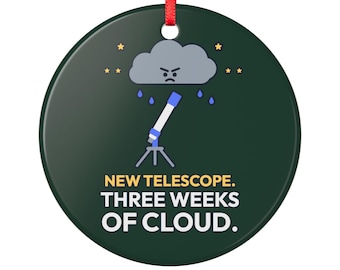 May include: A round dark green ornament with a red ribbon hanger. The design features a gray angry cloud raining on a white and blue telescope. The text reads: NEW TELESCOPE. THREE WEEKS OF CLOUD. Small yellow stars are scattered around the cloud.