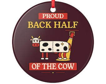 May include: A round dark maroon ceramic ornament with a red ribbon hanger. It features a graphic of a white cow with black spots, a red face, and yellow horns. Above and below the cow, the text reads PROUD BACK HALF OF THE COW.
