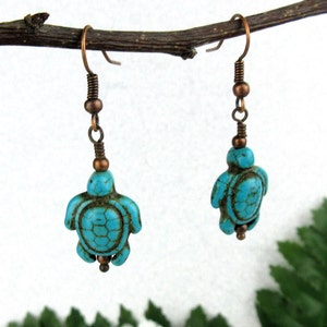 May include: A pair of turquoise blue turtle earrings with copper wire and beads hanging from copper hooks.