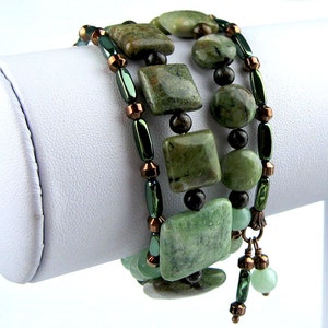 May include: A multi-strand wrap bracelet featuring square and round green mottled stone beads, interspersed with metallic copper-toned spacers and elongated dark green cylindrical beads, finished with two small dangling green stone charms.