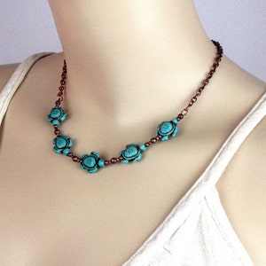 May include: A turquoise and copper necklace with turtle-shaped beads. The necklace is on a white background.