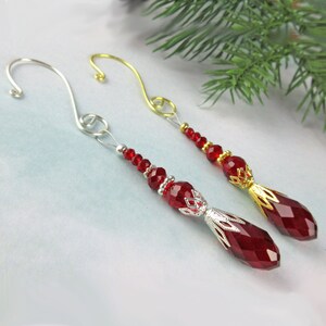 May include: Two red crystal Christmas ornaments with silver and gold accents. Each ornament has a wire hanger and is strung with red beads.