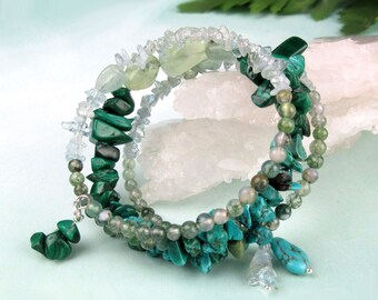May include: A multi-strand bracelet made with turquoise, malachite, and aquamarine stones. The bracelet is wrapped around a white crystal and has a silver charm.