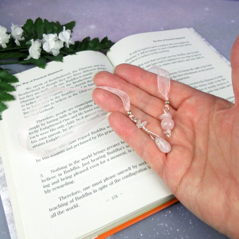 May include: Two handmade bookmarks with pink rose quartz beads and silver-tone accents. Each bookmark has a sheer pink ribbon for easy placement in a book. The bookmarks are displayed open on a book.