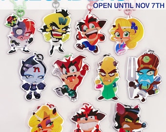May include: A collection of eleven acrylic character keychains featuring various cartoon figures from the Crash Bandicoot series, including Crash, Coco, and Dr. Neo Cortex. The text PREORDERS OPEN UNTIL NOV 7TH is displayed at the top.