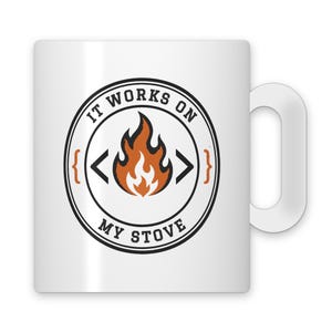 May include: A white ceramic mug featuring a circular black graphic with an orange flame icon in the center. The text "IT WORKS ON MY STOVE" is printed in black capital letters around the flame, flanked by orange curly brackets.