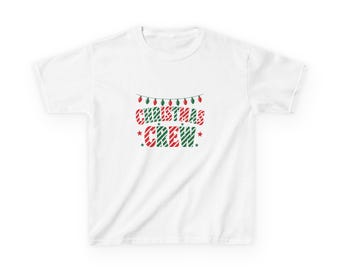 May include: A white short-sleeved t-shirt featuring a graphic of a string of red and green Christmas lights above the text "CHRISTMAS CREW" in a red and green striped pattern, accented by small red and green stars on the sides.