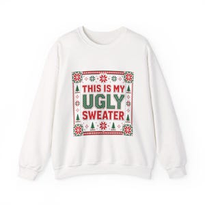 Puede incluir: Una sudadera blanca de manga larga con un gráfico rectangular central que presenta patrones navideños en rojo y verde, incluyendo copos de nieve y pinos, y el texto "THIS IS MY UGLY SWEATER" en letras rojas y verdes.