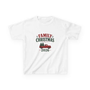 May include: A white short-sleeved t-shirt featuring a graphic with the text FAMILY CHRISTMAS in red and dark green. Below the text is a red and black buffalo plaid pickup truck carrying two green pine trees, with the year 2026 below.