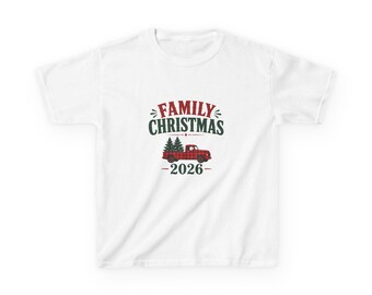 May include: A white short-sleeved t-shirt featuring a graphic with the text FAMILY CHRISTMAS in red and dark green. Below the text is a red and black buffalo plaid pickup truck carrying two green pine trees, with the year 2026 below.