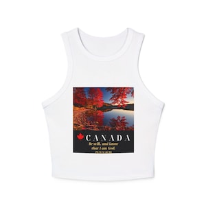 May include: A white sleeveless crop top featuring a rectangular graphic of a Canadian lake surrounded by red autumn trees. Below the image, the text reads CANADA with a red maple leaf icon, followed by the words Be still, and know that I am God. PSALM 46:10.