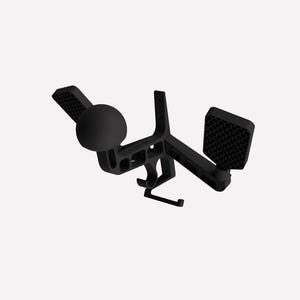 May include: A matte black wall-mounted controller and headset holder featuring a central spherical mount, two side arms with textured hexagonal grip pads, and a lower hook for cable management, constructed with a rigid geometric frame.